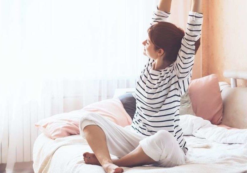 a woman sketching her arms on the bed in the morning | Feature | How to Have More Energy In the Morning