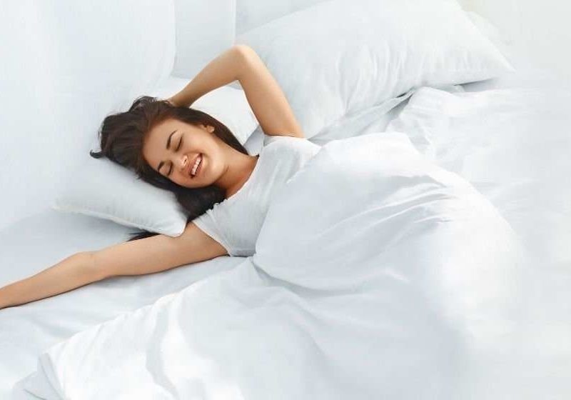 Young-beautiful-woman-waking-up-in-her-bed-fully-rested | Feature | 12 Tips for Waking Up Earlier and in a Better Mood