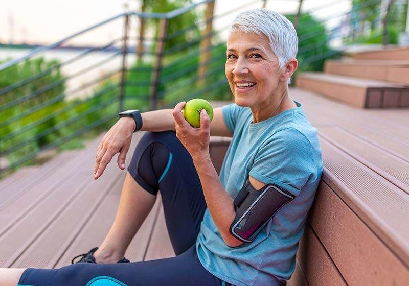 woman eating apple in her athletic outfit | feature | How To Maintain A Healthy Weight?