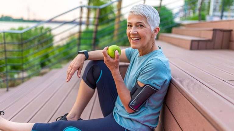 woman eating apple in her athletic outfit | feature | How To Maintain A Healthy Weight?