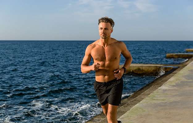 A fit middle aged man running along the beach | What Are the Benefits of BHRT, and Is It Right for You?