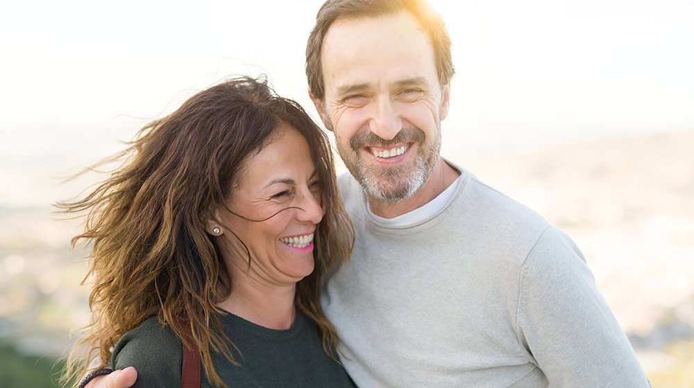 A happy middle aged couple under sunshine near the lake | Feature | What Are the Benefits of BHRT, and Is It Right for You?