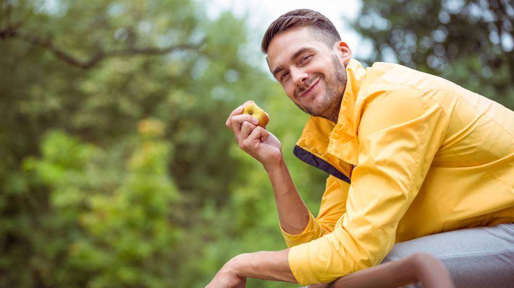 happy guy eating apple 5 Surprising Benefits Of Collagen For Men feat ss
