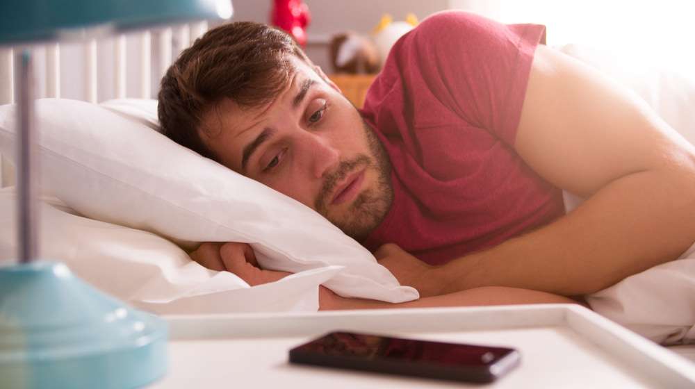 man bed woken by alarm on How to Wake Yourself Up and Prevent an Afternoon Slump