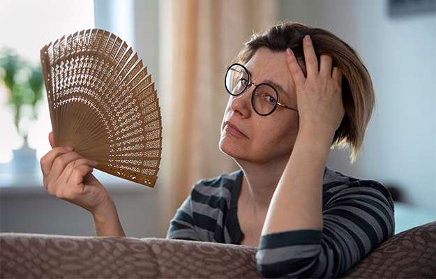 woman-waving-her-fan-Menopause-Is-Being-Mistreated-or-Misdiagnosed-ss-body