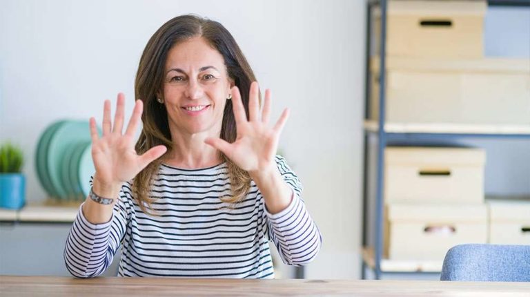 Middle-aged-woman-sitting-at-the-table-at-home-showing-palms-of-hands---10-Symptoms-of-Low-Estrogen-in-Women