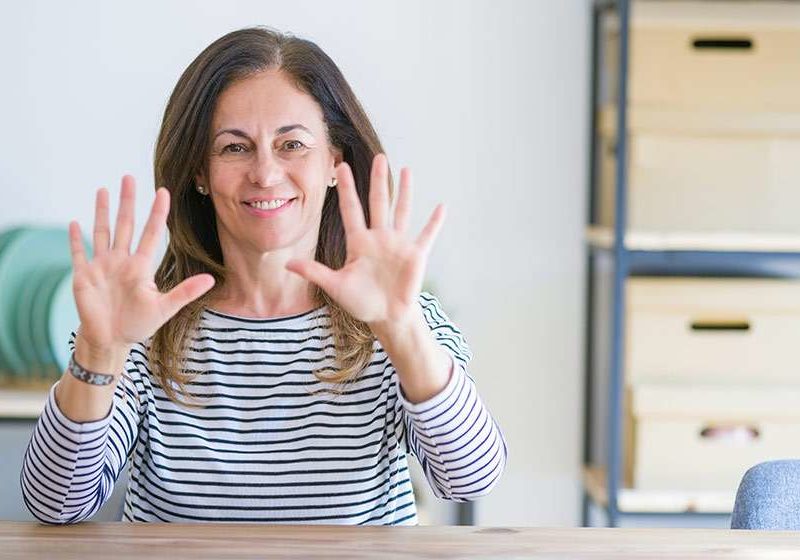 Middle-aged-woman-sitting-at-the-table-at-home-showing-palms-of-hands---10-Symptoms-of-Low-Estrogen-in-Women