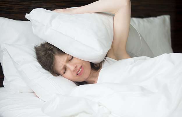woman-lying-in-bed-and-covering-her-ears-Understanding-Menopause-Symptoms