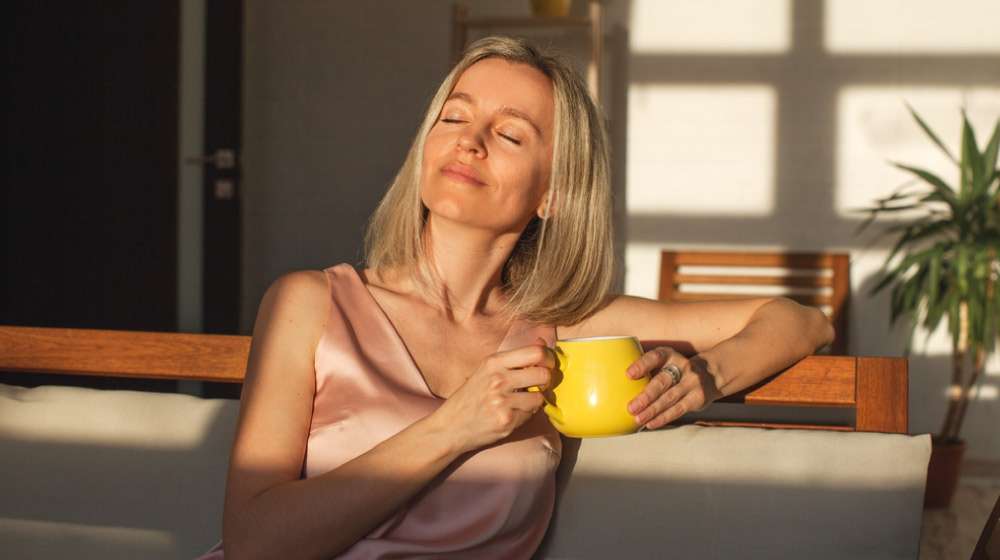 Smiling woman sitting in the sun with mug