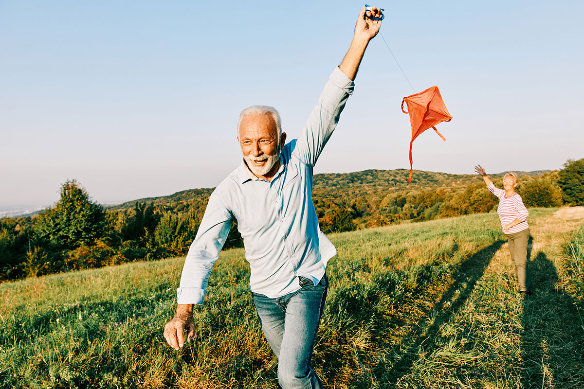 Older man flying a kite in a field after peptide therapy