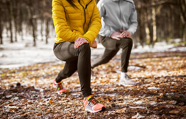 Close-up-of-shape-fitness-girl-in-sportswear-doing-leg-stretching-with-her-personal-trainer-in-the-forest-in-the-sunny-winter-morning.-What-Is-PEMF-Therapy-Used-For