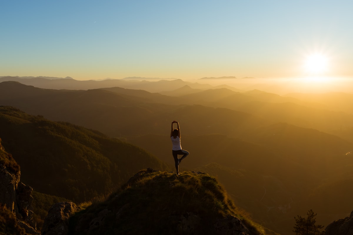 Person in tree pose on a mountain at golden hour - Yunique Medical