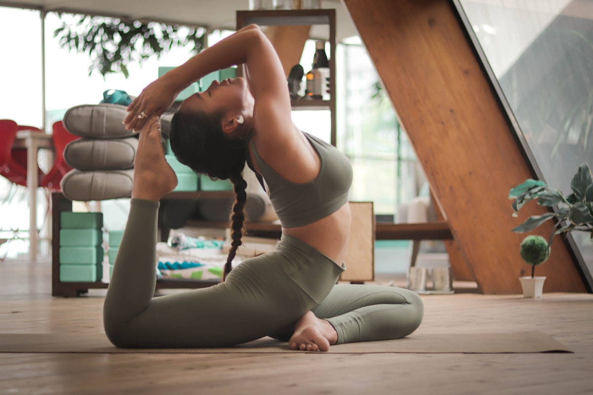 Woman in elegant yoga pose in a sunlit studio - Yunique Medical