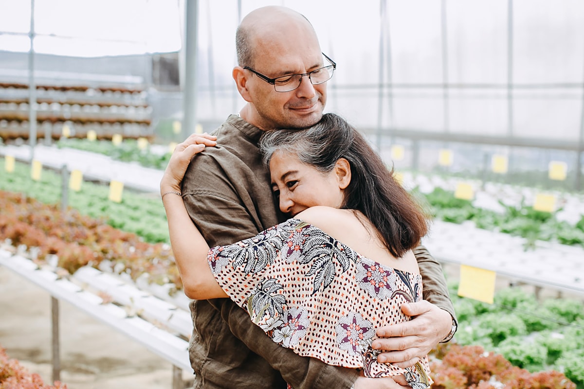 Couple sharing a warm embrace in a greenhouse - Yunique Medical