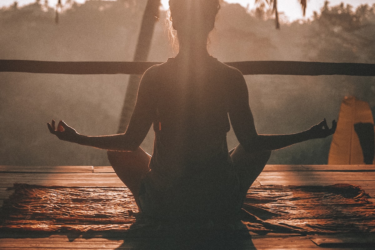 Silhouette of person meditating at sunrise - Yunique Medical