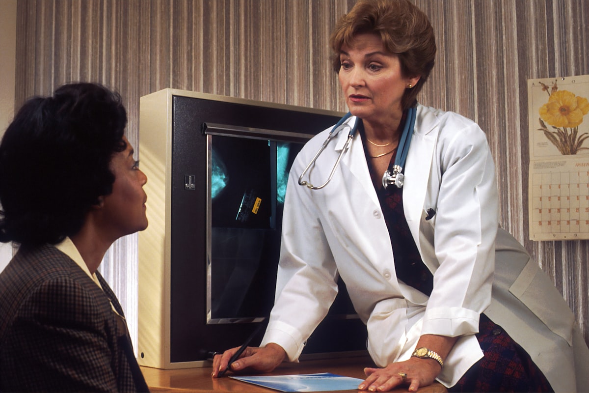 Physician in a white coat speaking with a patient across a desk - Yunique Medical