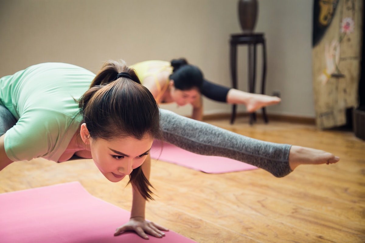 Women performing plank exercises on yoga mats in a fitness studio
